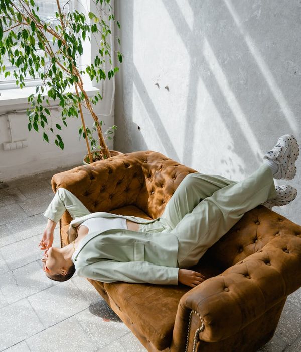 A serene woman in a comfortable yoga pose in a bright, sunlit room.